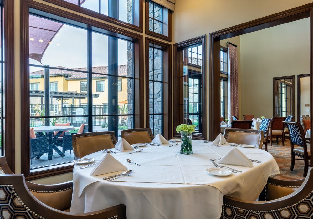 An elegantly set dining table by large windows in a cozy restaurant.