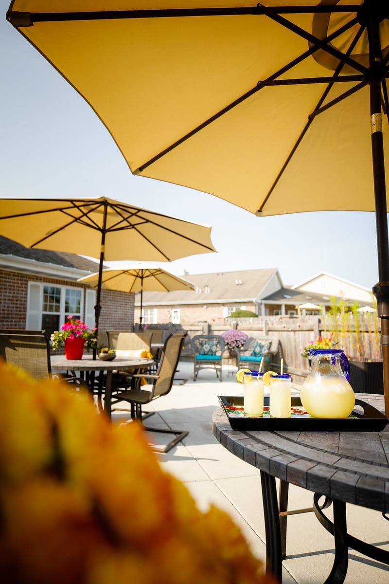 A sunny patio with umbrellas, tables, and chairs set for a relaxing outdoor gathering.