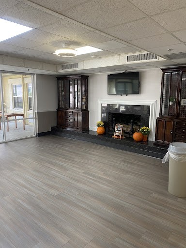 A spacious and modern living area featuring wooden cabinets, a television mounted on the wall, and decorative elements.