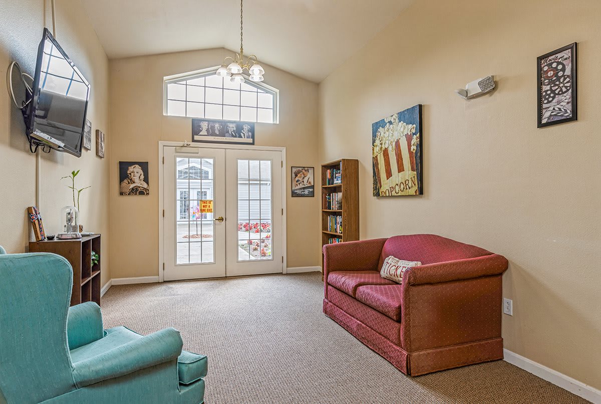 A cozy living room featuring comfortable sofas, artwork on the walls, and a bookshelf by the window.