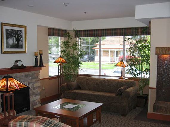 Cozy living room with a sofa, coffee table, fireplace, and large windows allowing natural light to enter.