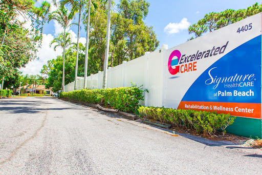 Entrance to a healthcare facility surrounded by palm trees and greenery.