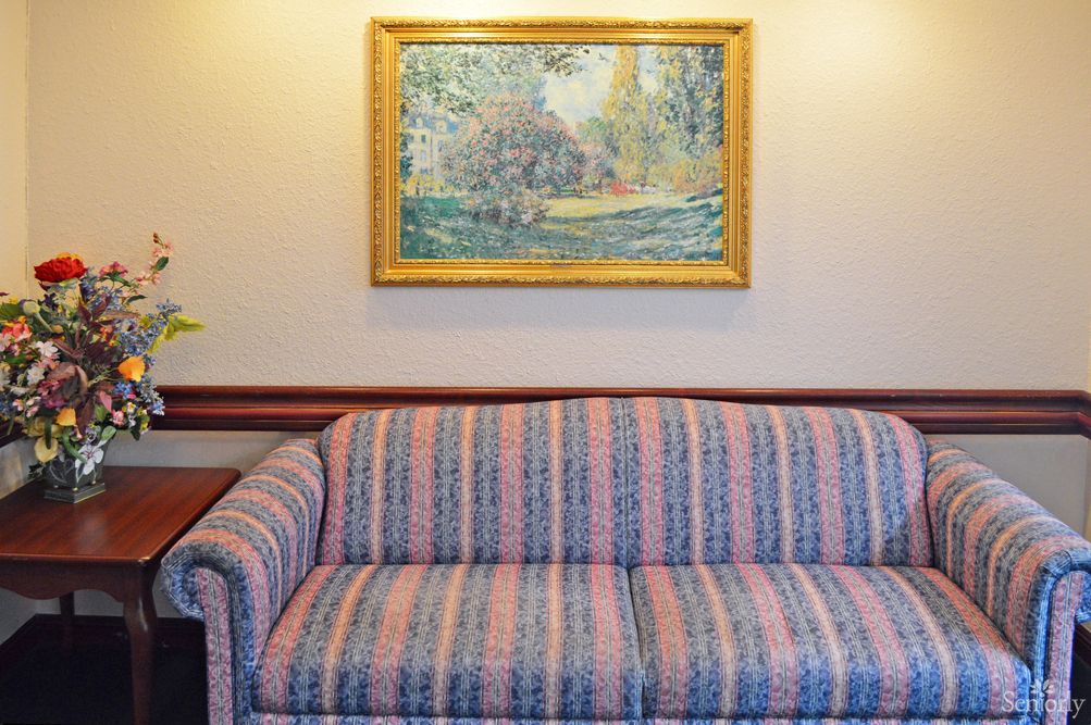 A cozy living room with a striped sofa and a framed painting on the wall.