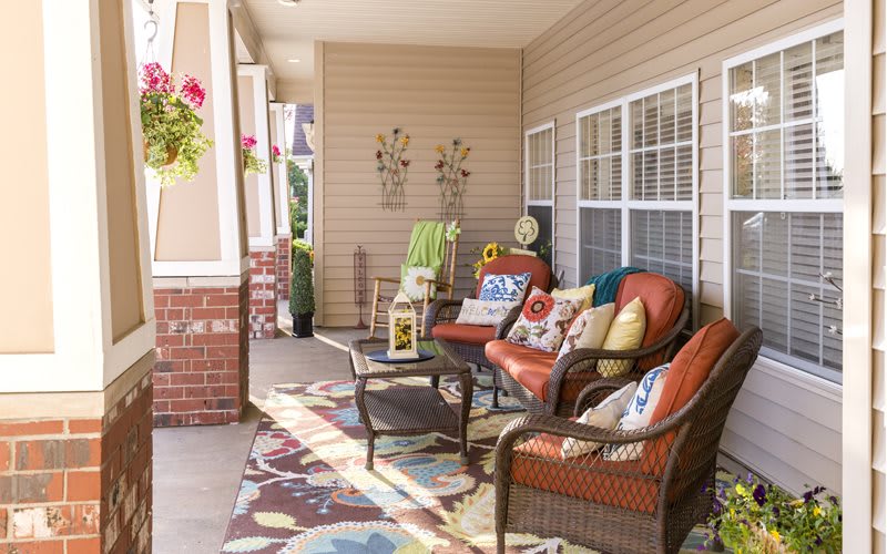 A cozy porch with wicker furniture, vibrant cushions, and decorative accents.