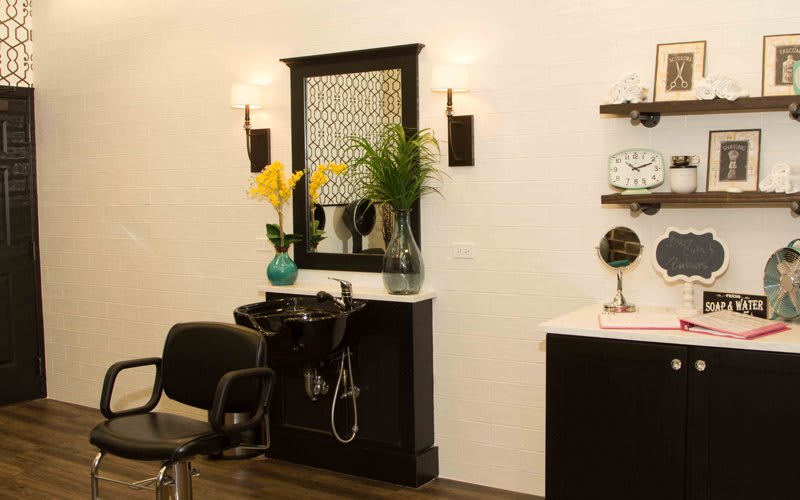A well-decorated hair salon interior with a styling chair, sink, and mirror.