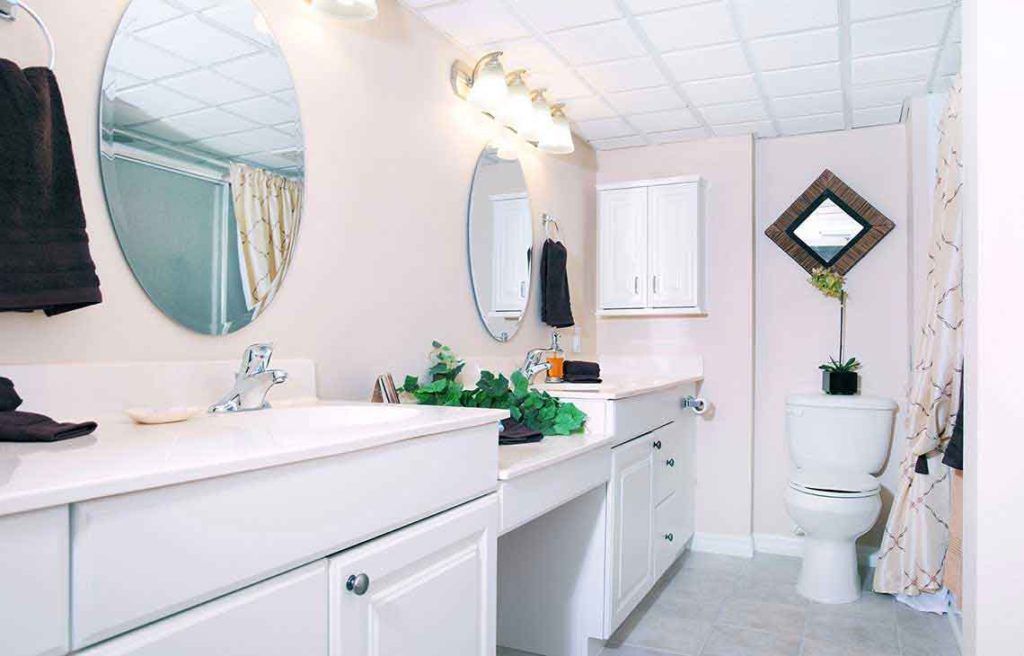 A modern bathroom with a large mirror, sink, and cabinets.