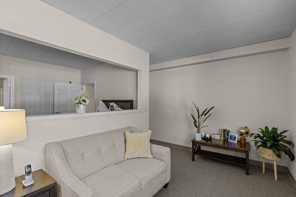 A modern living room with a neutral color palette, featuring a sofa and a coffee table adorned with decorative items.