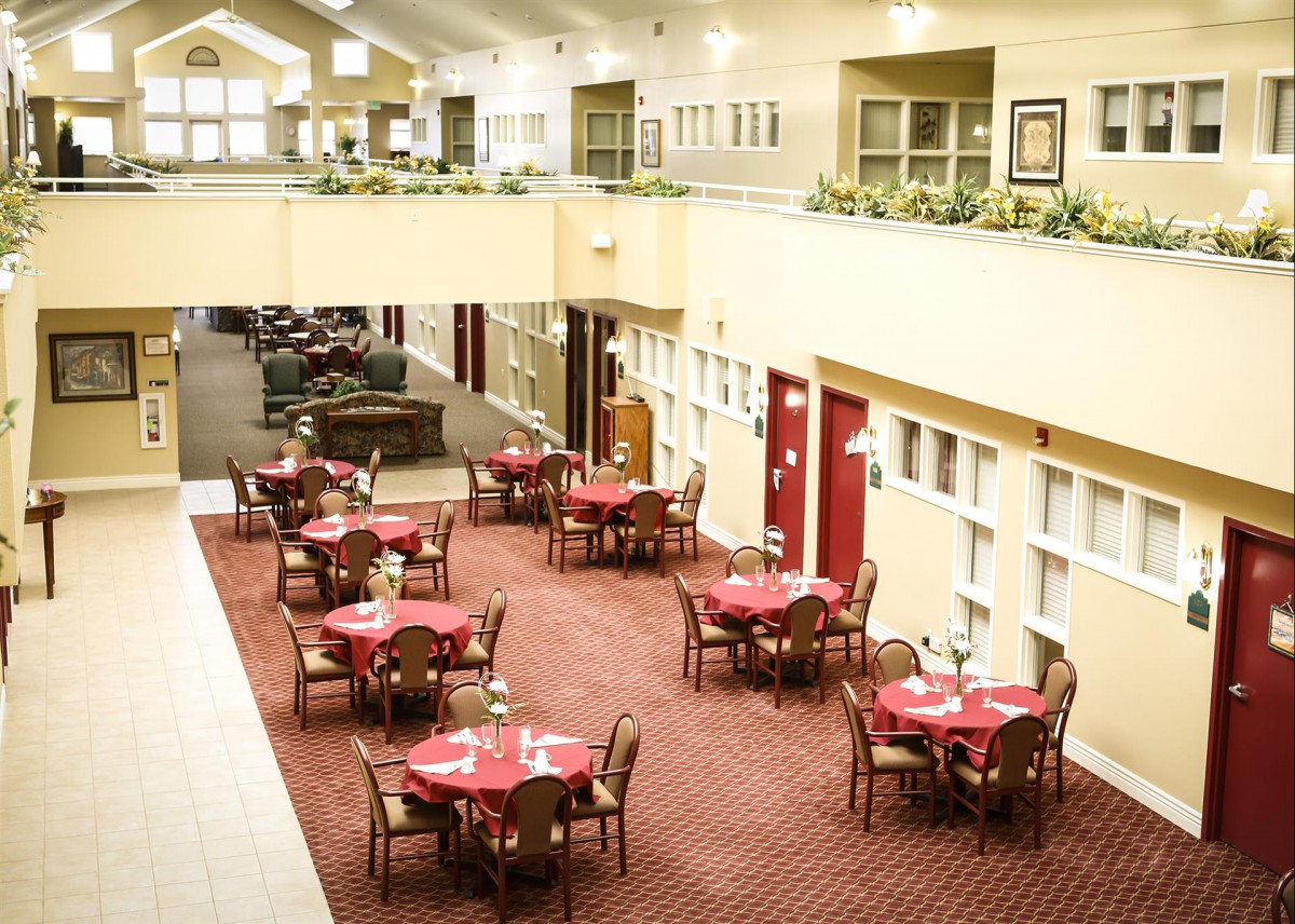 An indoor dining area with multiple tables and chairs arranged on a carpeted floor.