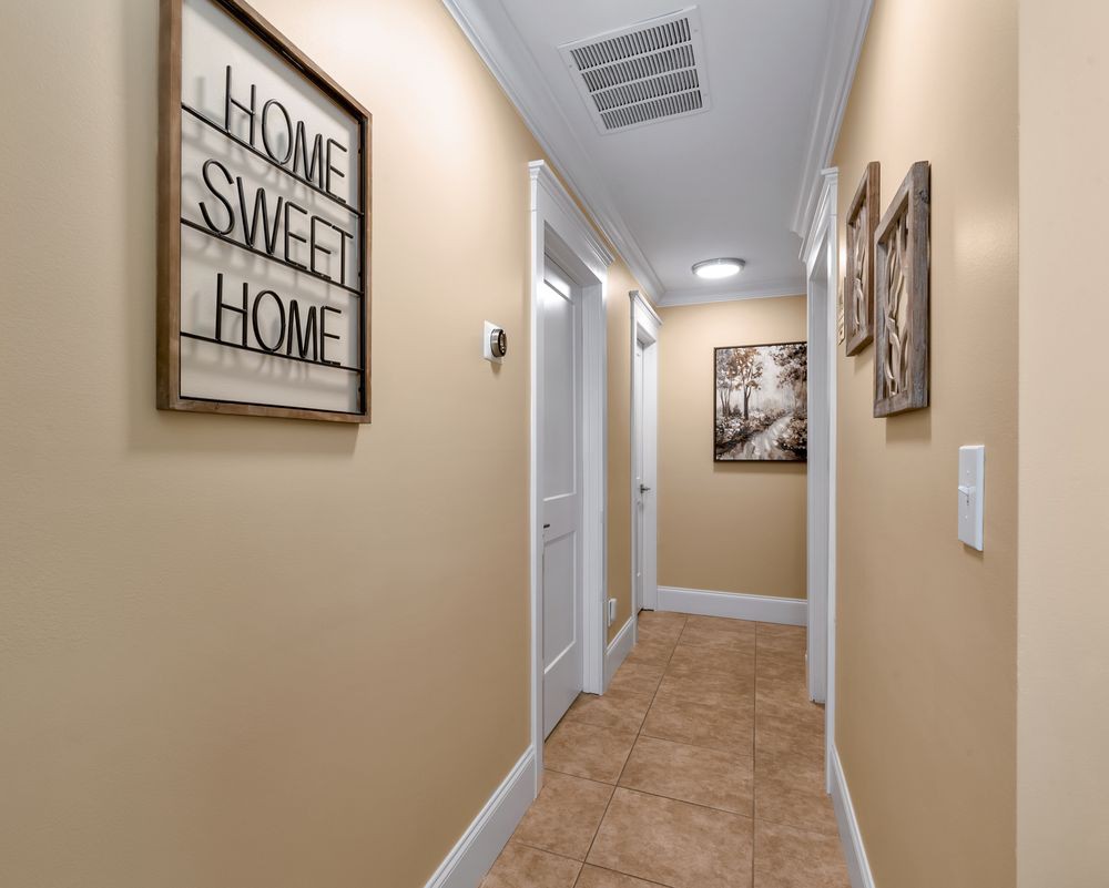 A cozy hallway with warm lighting and decor, featuring a 'Home Sweet Home' sign.