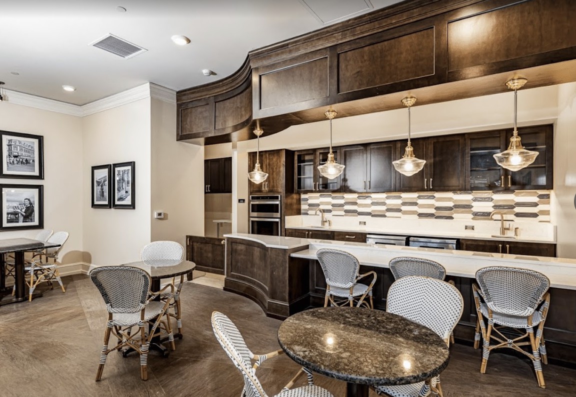 A modern kitchen and dining area with wood cabinets, pendant lighting, and granite countertops.
