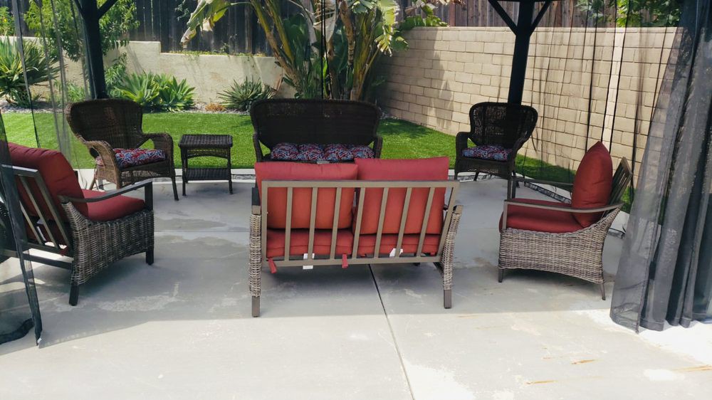 Outdoor patio set with cushioned chairs and sofa in a garden setting.