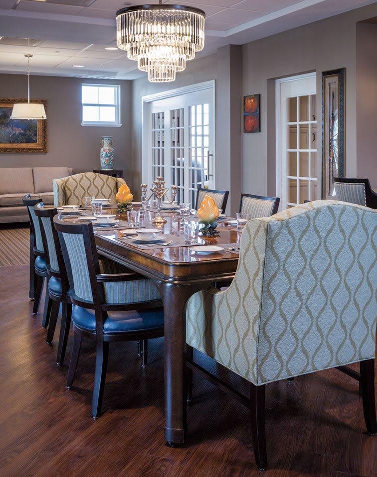 Elegant dining room with a large table and plush chairs under a chandelier.
