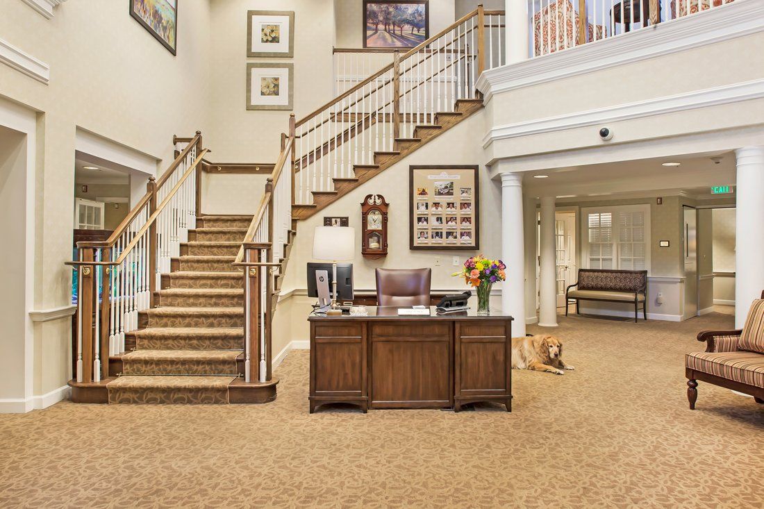 A welcoming lobby area featuring a central desk, elegant staircase, and decorated walls.