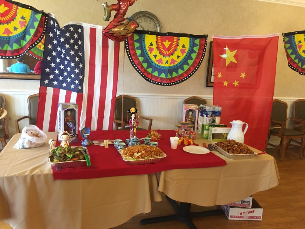 A table adorned with American and Chinese flags, featuring a variety of foods, set up for a cultural event.