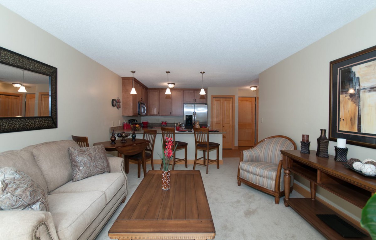A cozy living area with a connecting kitchen, featuring comfortable furniture and inviting decor.