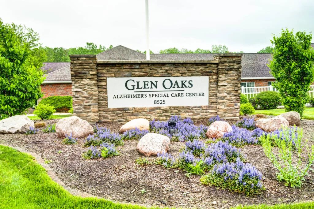 Entrance sign for Glen Oaks Alzheimer's Special Care Center surrounded by landscaped flowers.