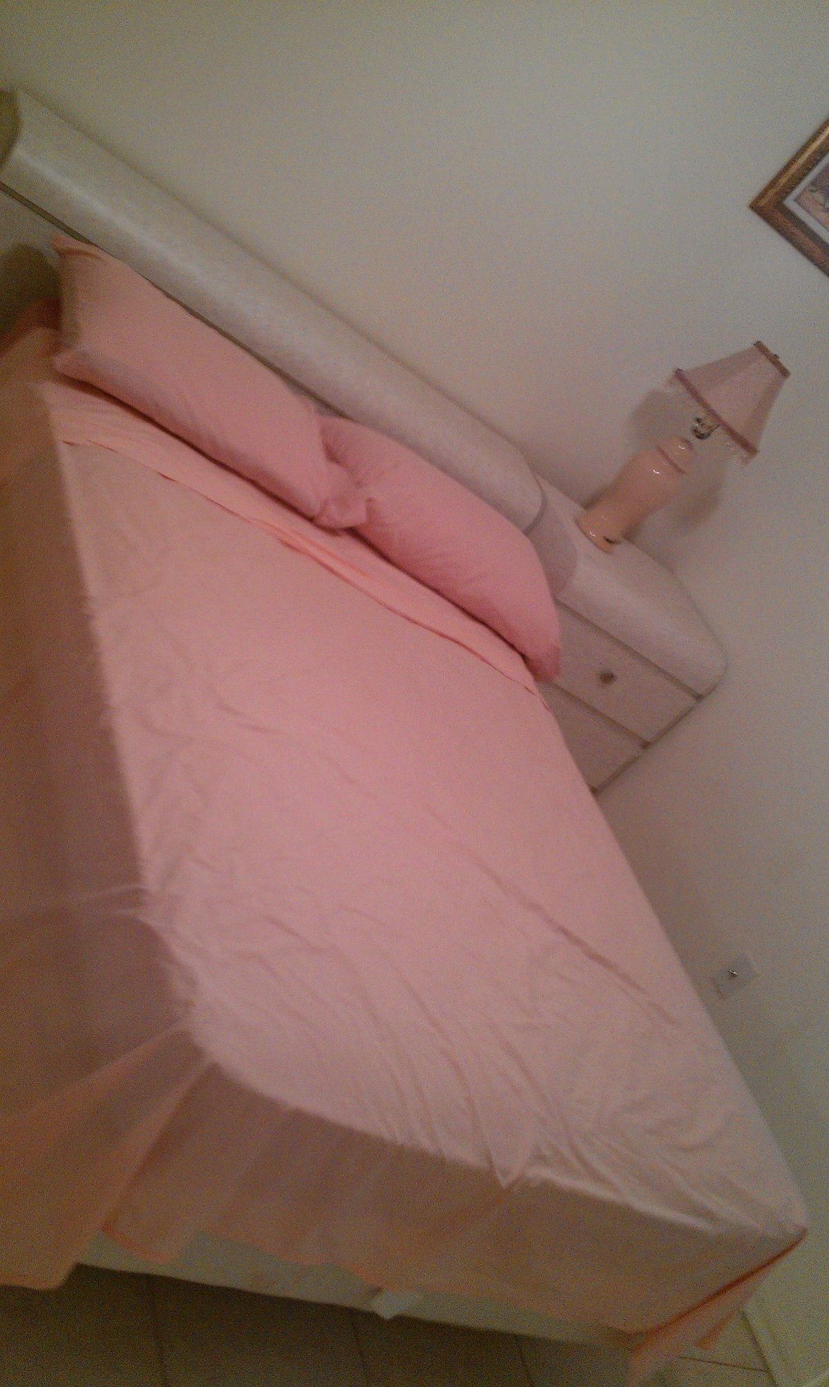 A cozy bedroom with a pink bedspread and matching pillows.