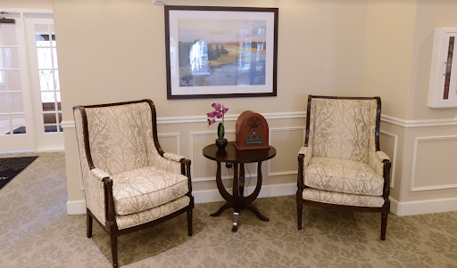 A cozy seating area featuring elegant chairs, a decorative table with flowers, and wall art.