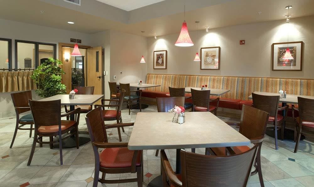 A cozy restaurant interior with neatly arranged tables and chairs, warm lighting, and subtle decor.