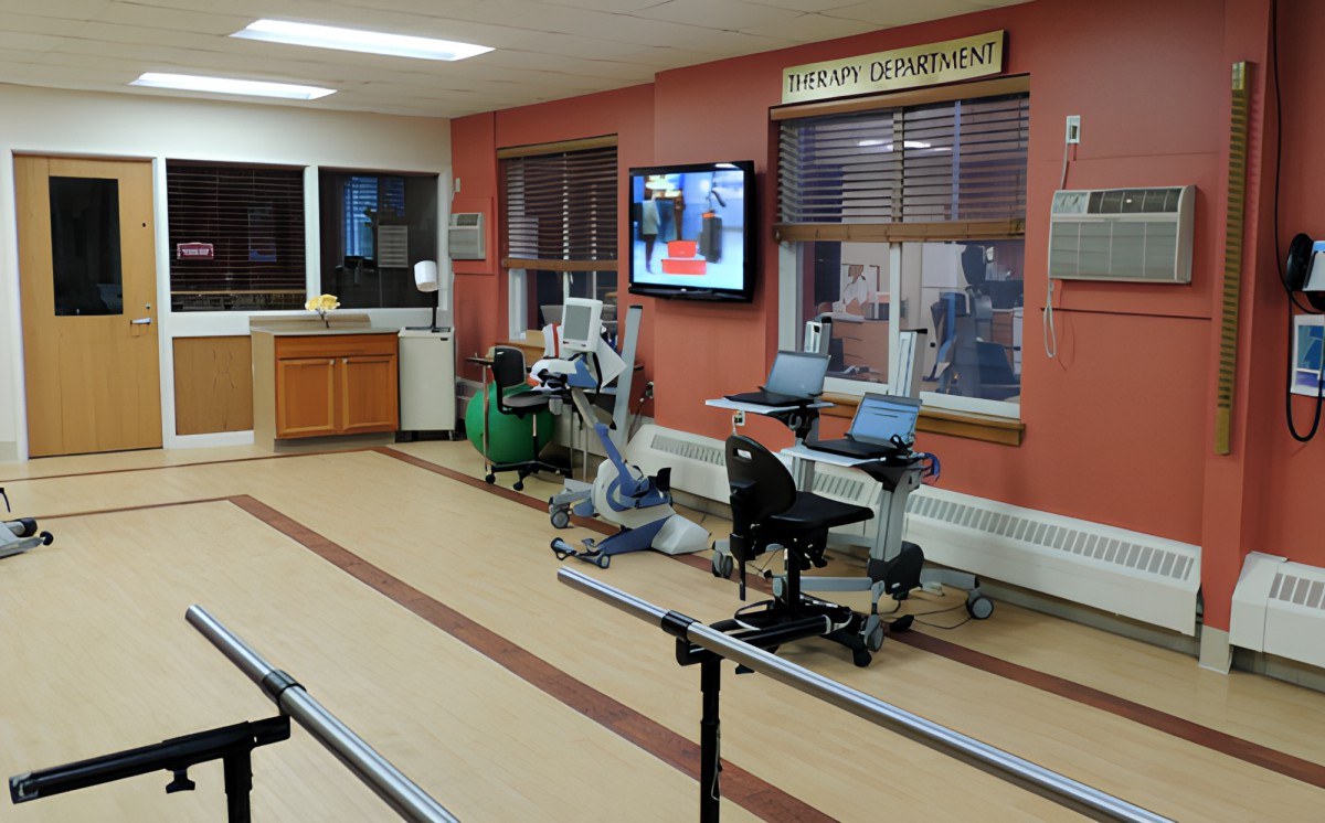 A physical therapy room equipped with exercise machines and parallel bars for rehabilitation.