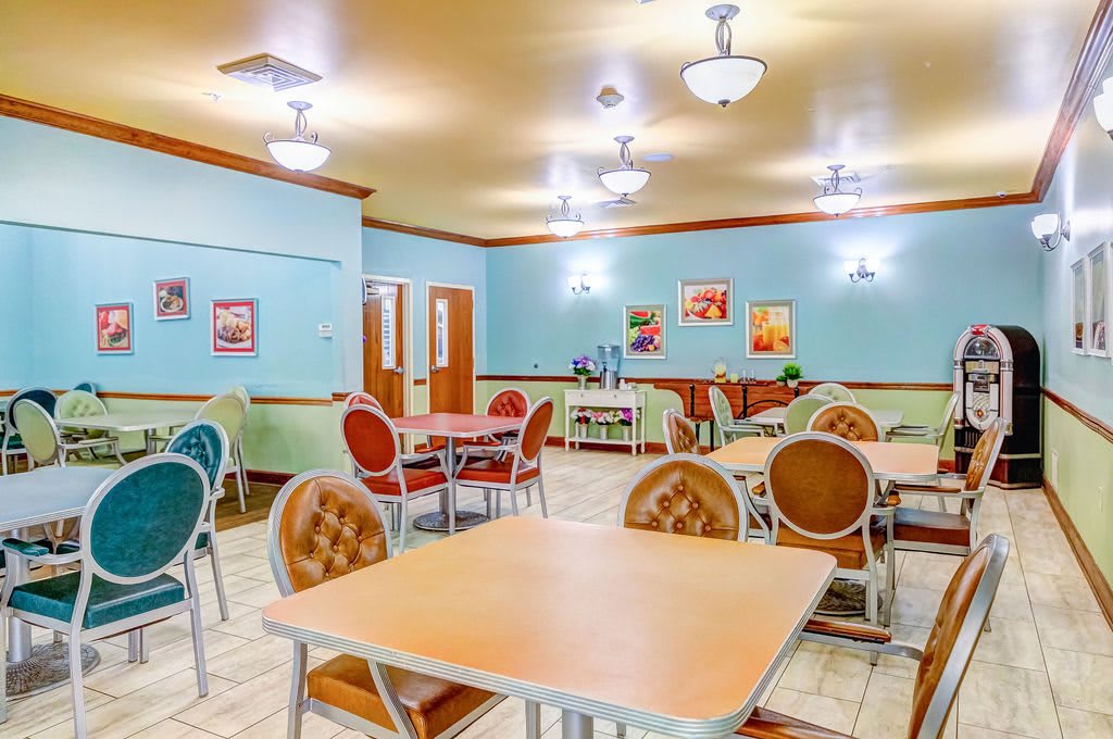 An empty dining room with colorful chairs and tables arranged neatly.