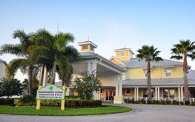 A brightly colored building with palm trees and a landscaped entrance.