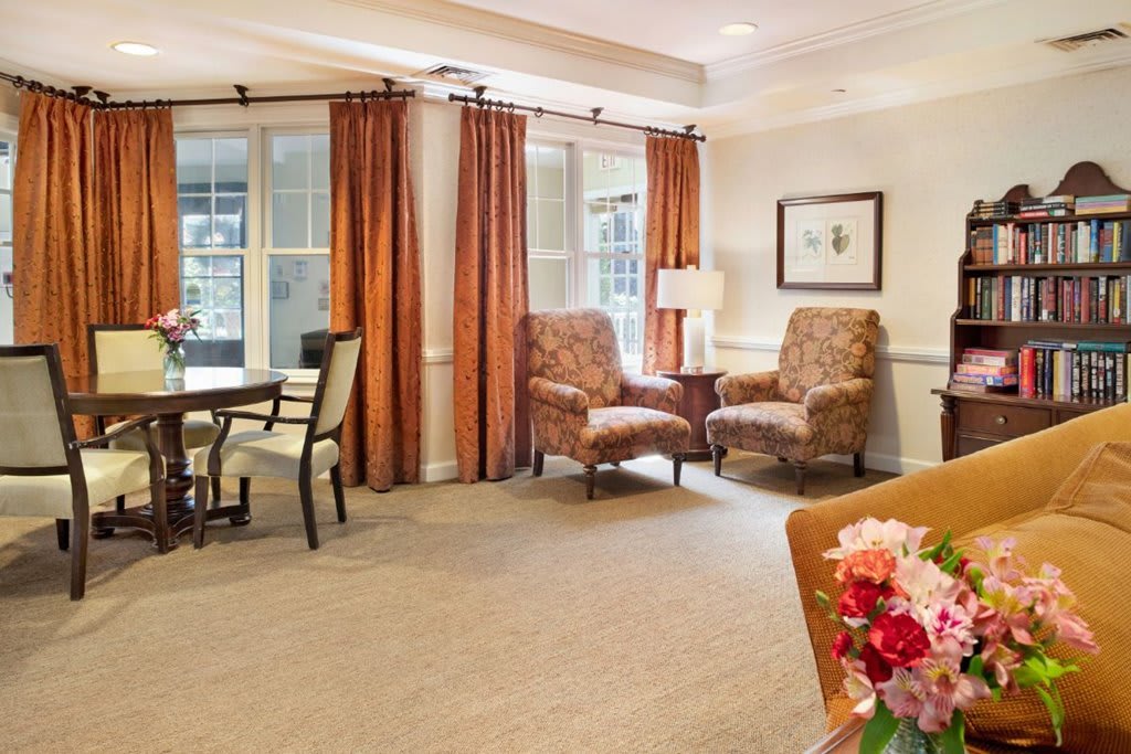 A cozy living room with two armchairs, a small table, and bright curtains.