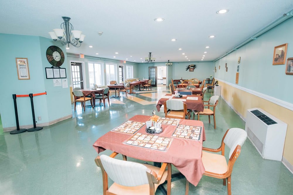 A well-organized dining room with neatly arranged tables and chairs, featuring pastel-colored walls and ample lighting.