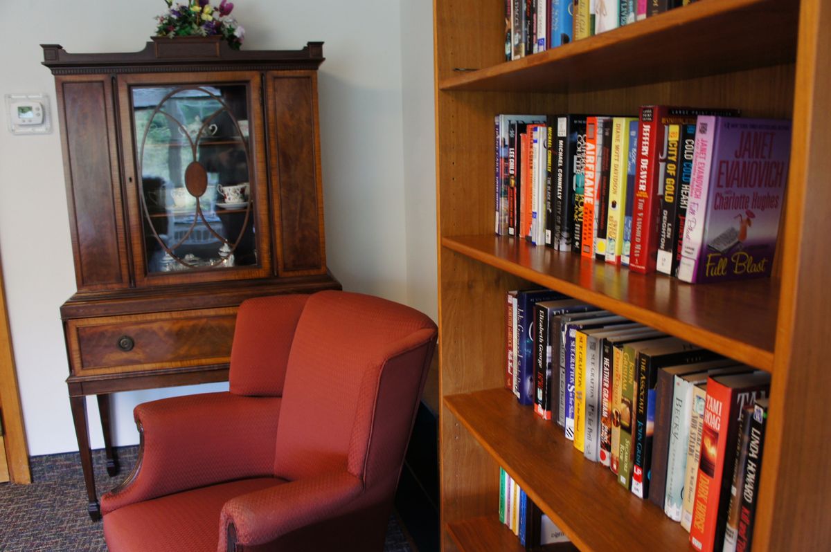 A cozy reading nook with a red chair next to a wooden bookshelf filled with books.