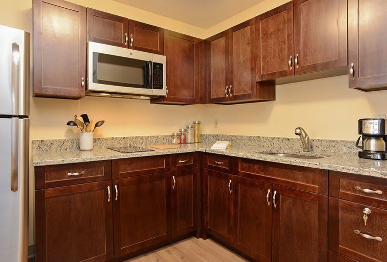A modern kitchen with wooden cabinets, a built-in microwave, and a granite countertop.