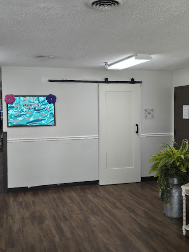 A modern office space featuring a sliding door, a television on the wall, and decorative plants.
