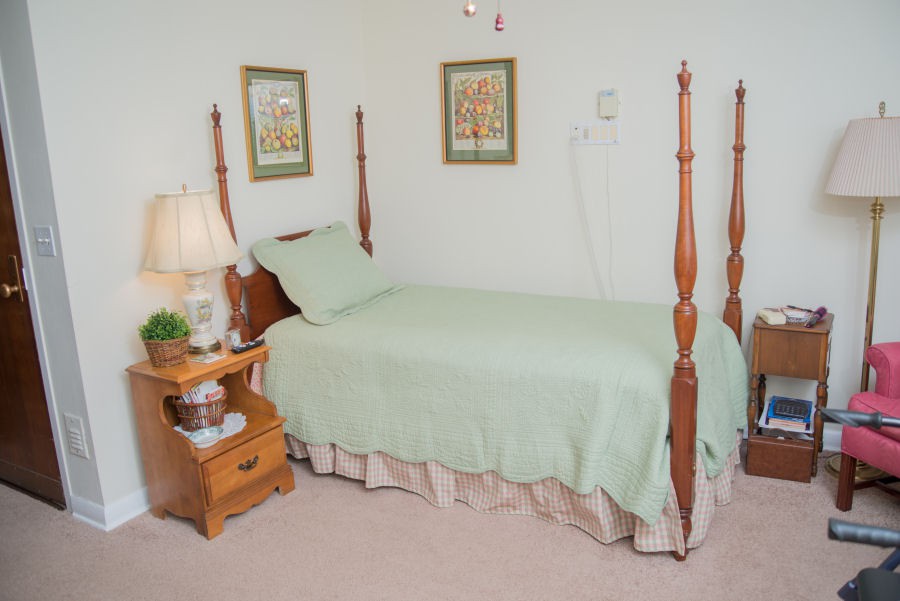 A cozy bedroom with a single four-poster bed, a wooden nightstand, and decorative wall art.