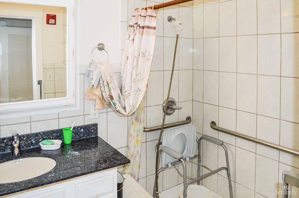 An accessible bathroom with a shower, equipped with grab bars and a shower chair.