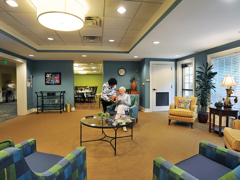 A cozy waiting area in a nursing home with a caregiver attending to an elderly person.