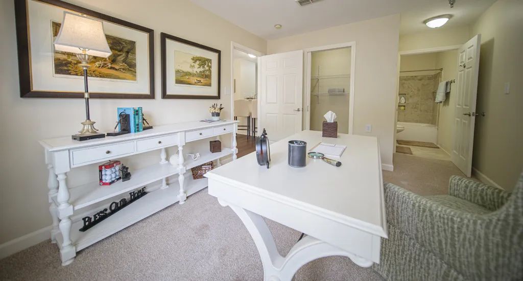 A bright and modern home office with a white desk and bookshelves, complemented by framed artwork on the walls.