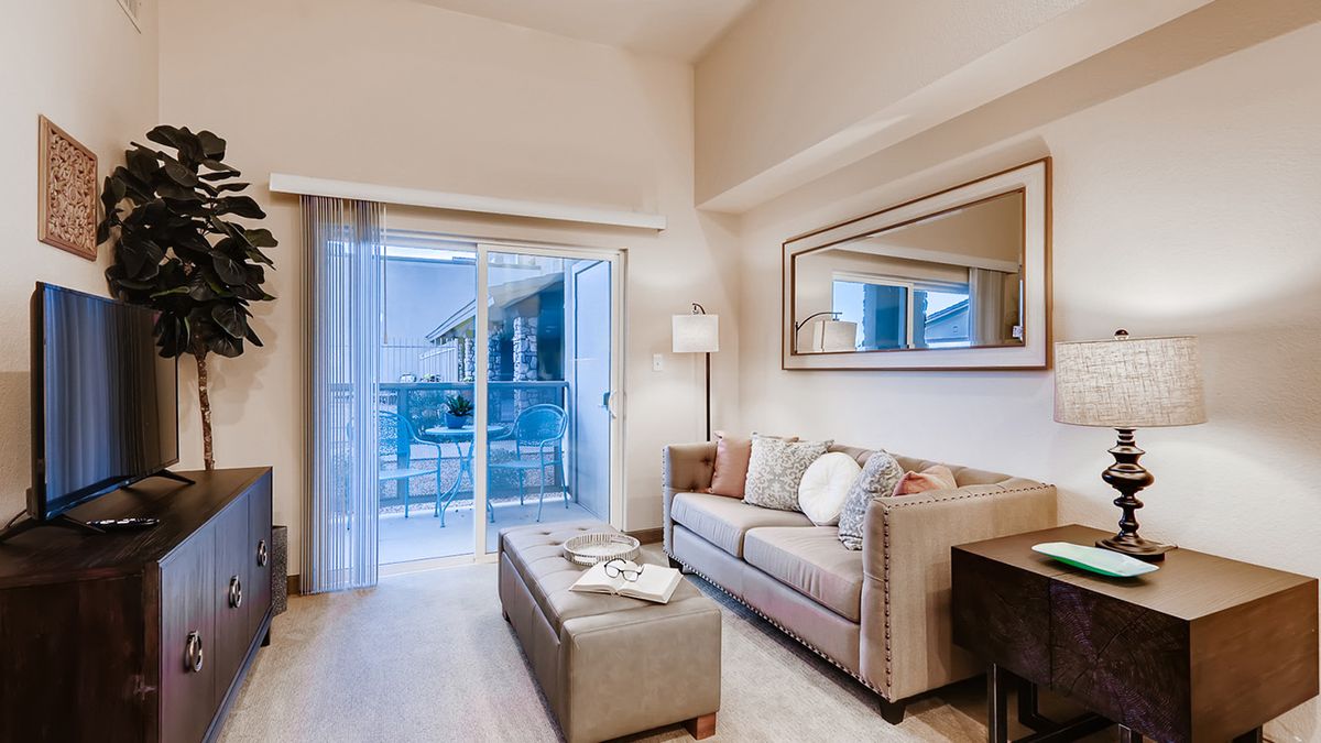 A modern living room with a comfortable sofa, coffee table, and a balcony view.