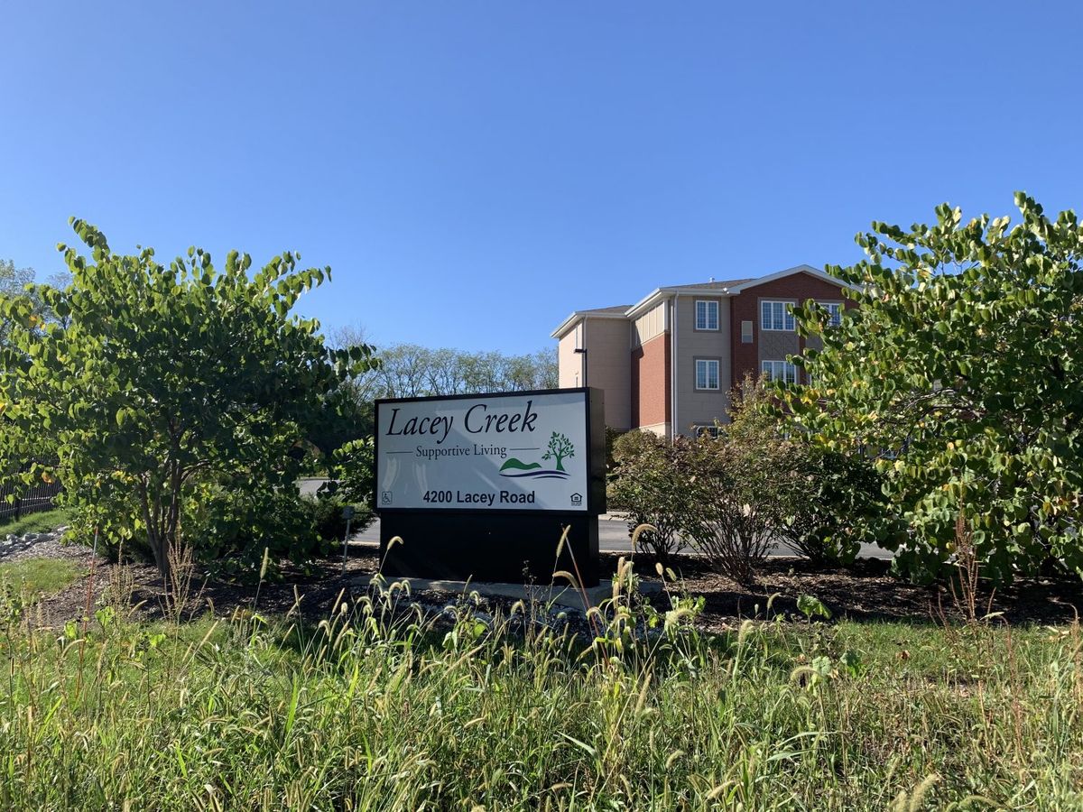 A sign for Cary Crest Apartments with a building and trees in the background.