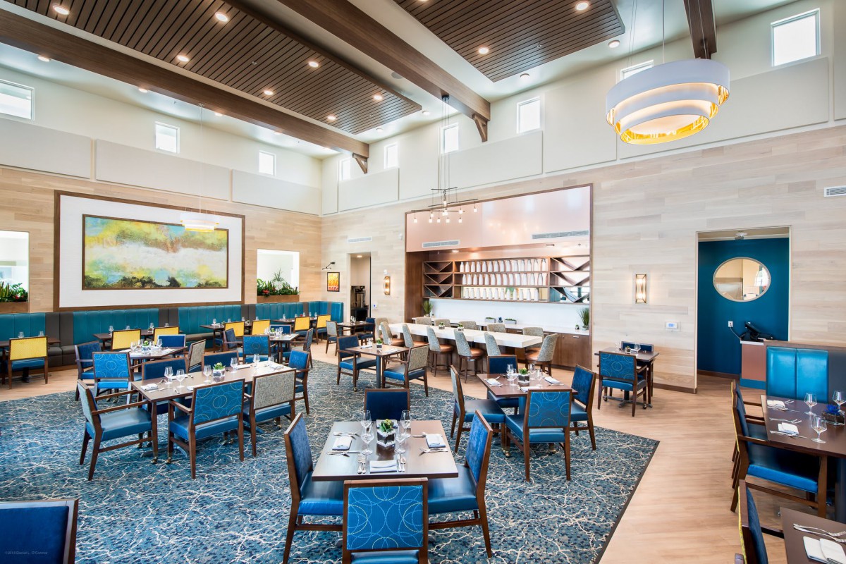 A modern restaurant interior with elegantly arranged tables and vibrant blue chairs.