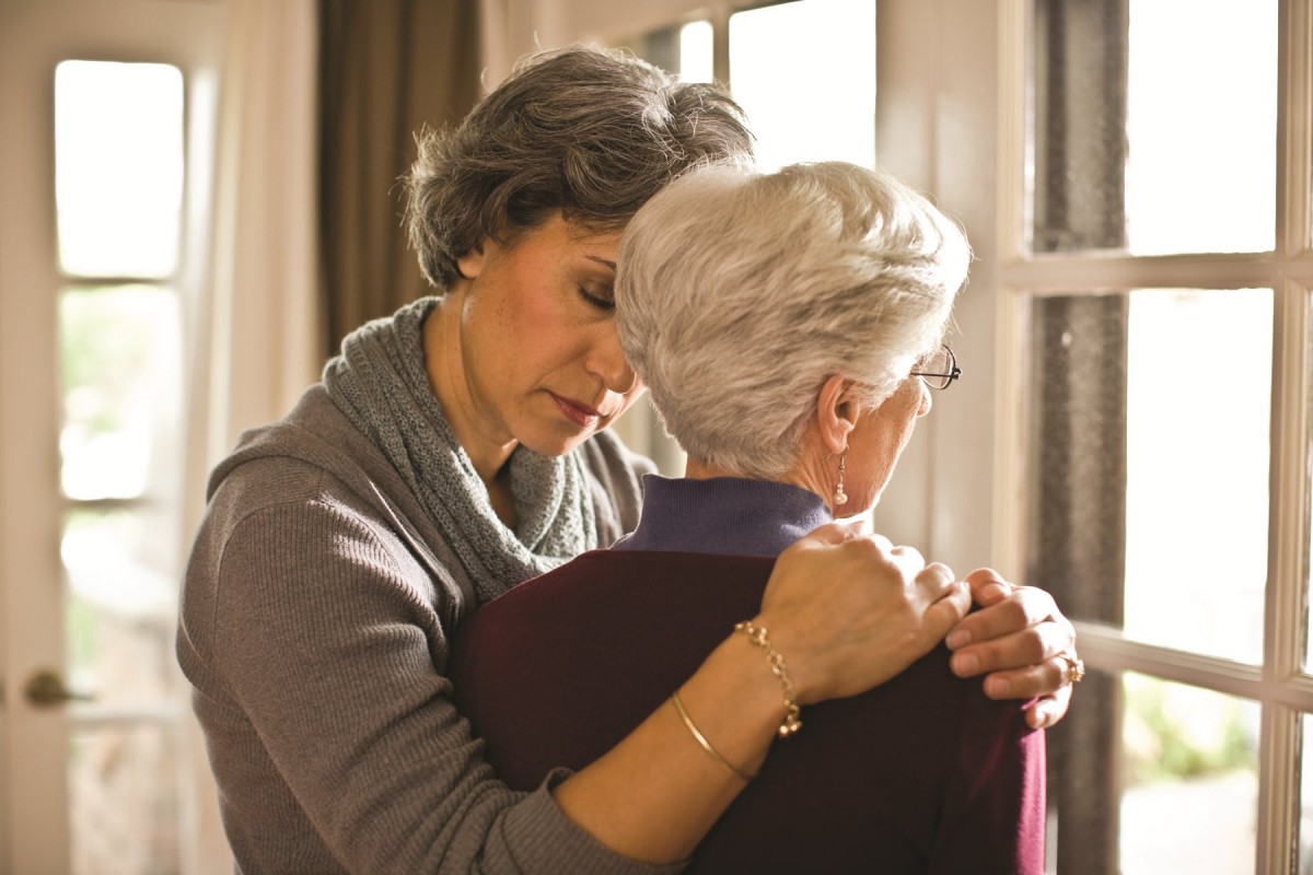 A woman embraces an elderly person, conveying support and comfort.