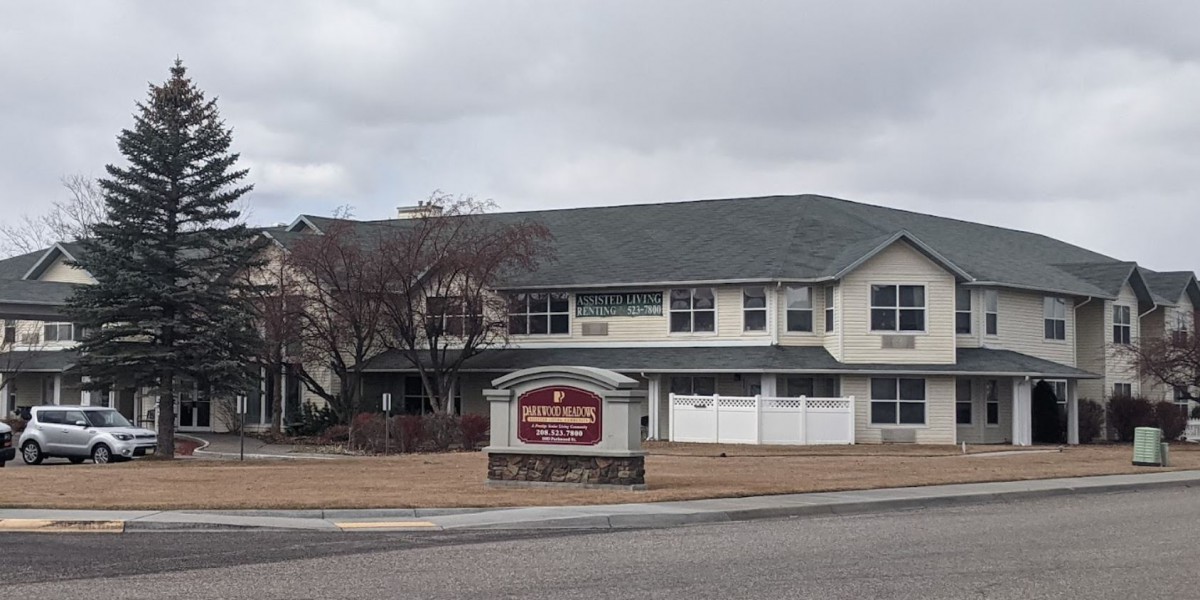 An overcast day at a two-story residential building with a sign in front.