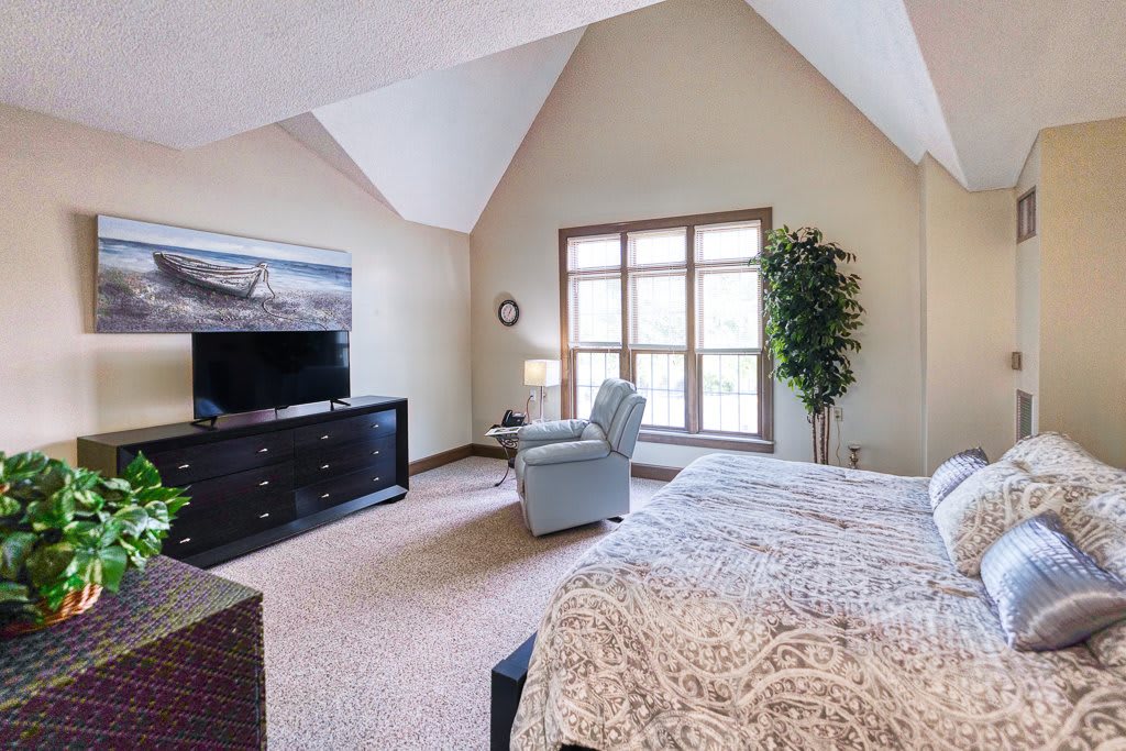 A spacious bedroom with elegant furnishings and large windows.