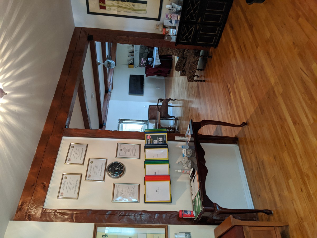 A cozy living room with wooden flooring, showcasing a wall adorned with certificates and artwork.