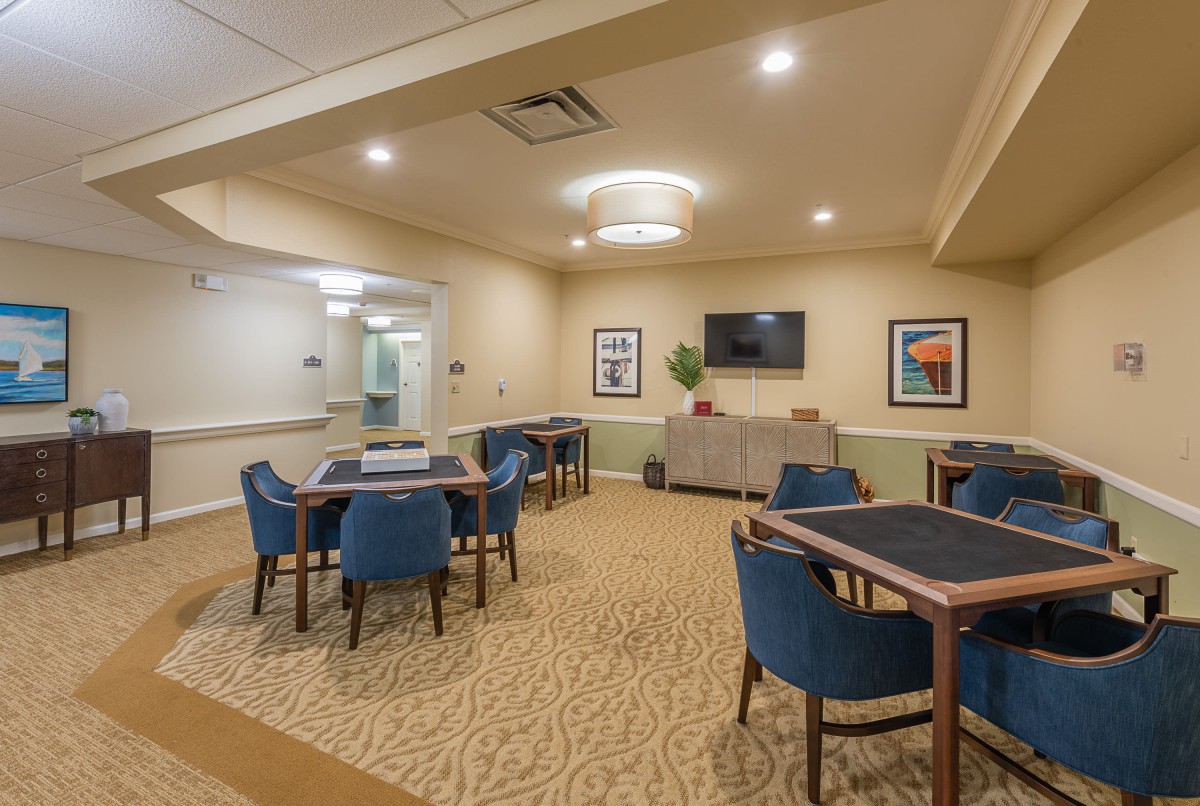A modern meeting room with chairs and tables arranged neatly, featuring bright lighting and minimalist decor.