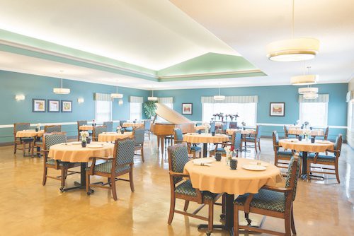 A spacious dining area with neatly set tables and a grand piano.