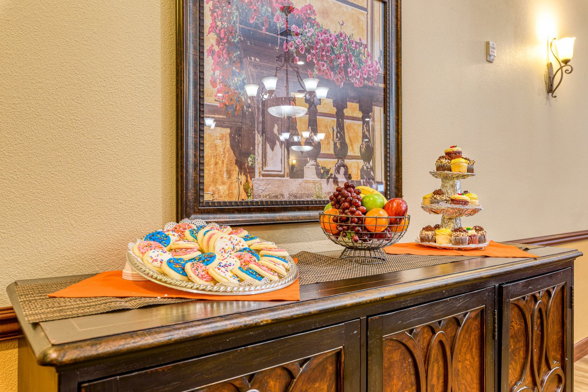 A buffet setup featuring a colorful fruit platter and decorated cookies, with art adorning the wall above.