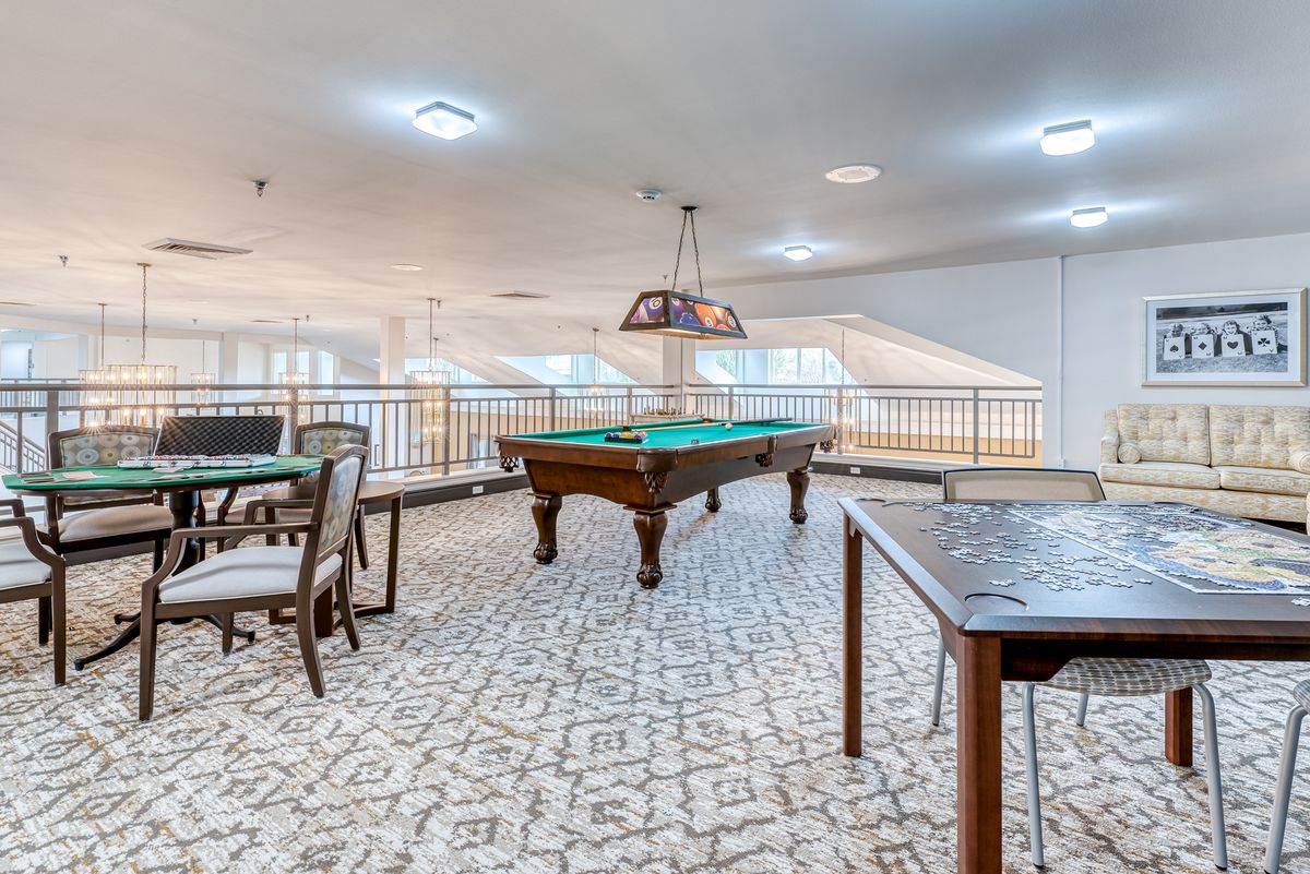 A well-furnished game room featuring a pool table and seating areas.