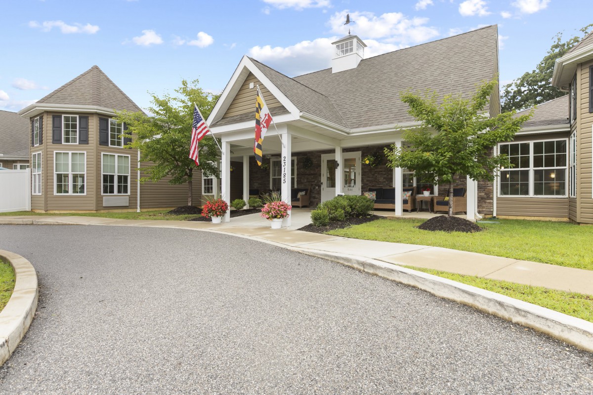 A well-maintained building entrance with flags and neatly landscaped surroundings.