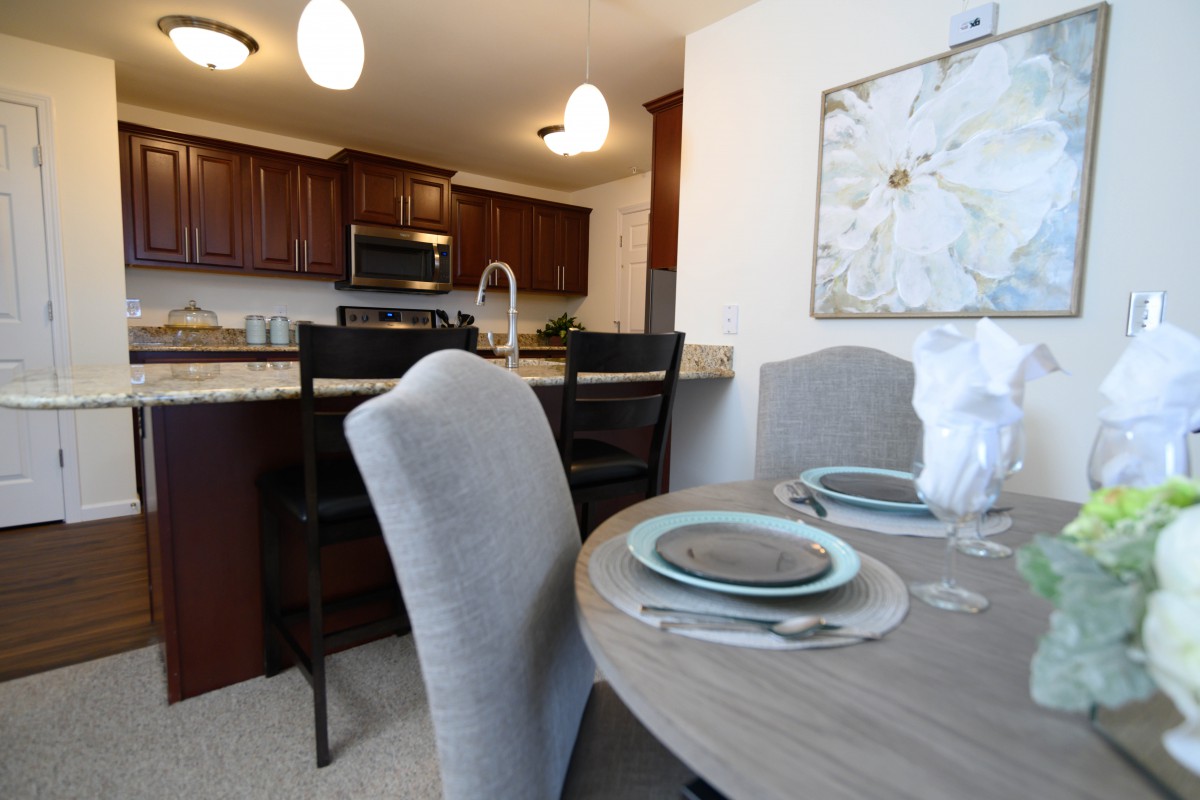 A modern dining area with a set table and a view of the kitchen.