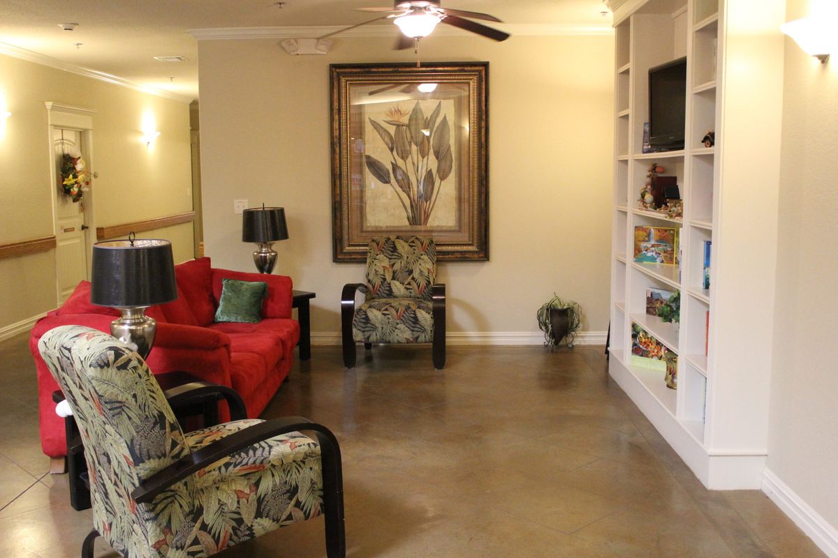 A cozy living room with a red sofa, floral armchairs, and a built-in bookshelf.