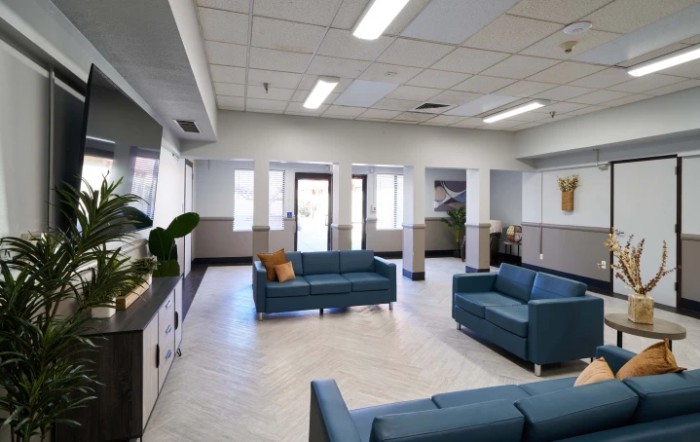 A modern waiting room with blue sofas and ample natural lighting.